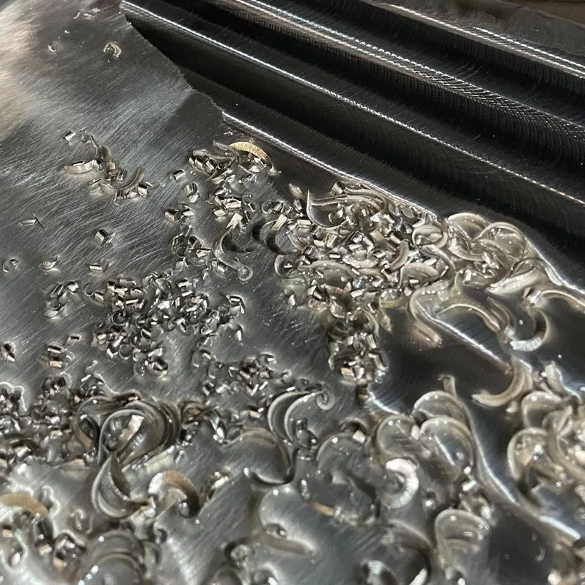 A metal block being milled, covered in bright curled chips